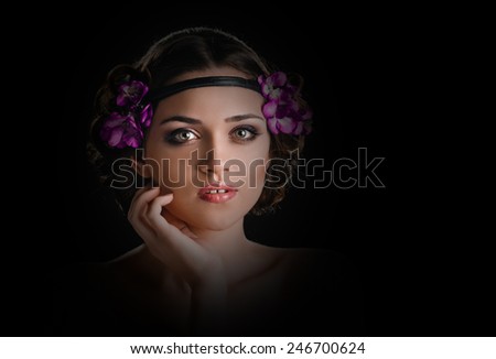 Beauty portrait of young woman with purple floral wreath over dark vignetting background