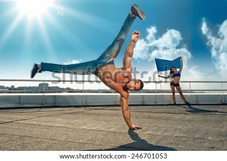 sport, dancing, man doing handstand, girl with flag on background, focus on man face