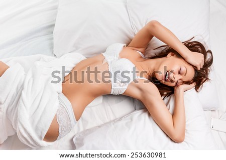 Above view of pretty female in peignoir lying on bed with smile