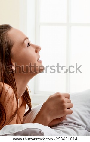 young girl laying in bedroom at early morning, in profile