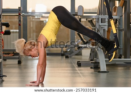 Young woman doing push-ups while legs hanging on elastic rope