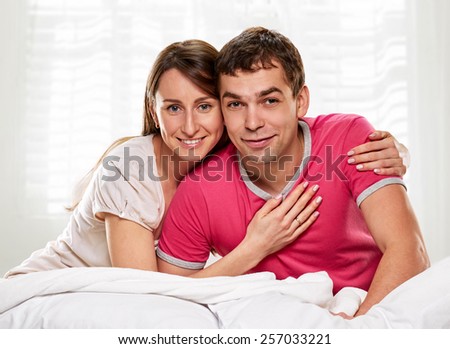 Happy smiling couple laying laughing in bed