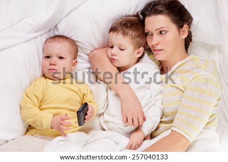 happy mother with her child on white bed, shot from above, little girl crying
