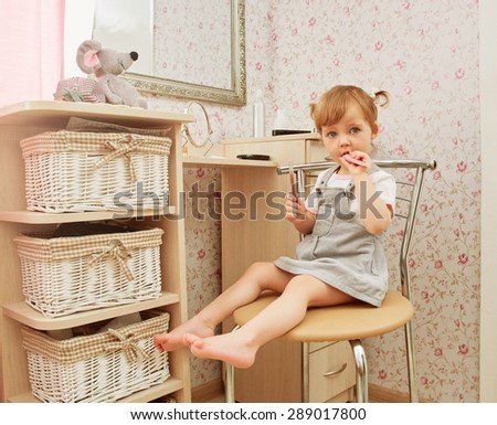 Adorable little girl playing with mommy\'s make up about make up table