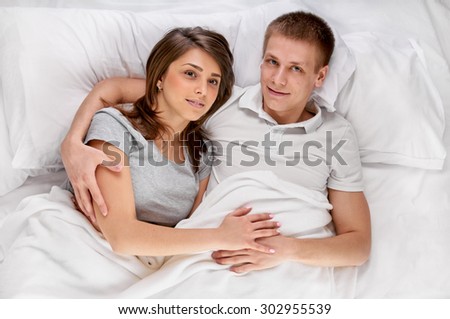Happy young couple lying in bed, shot from above