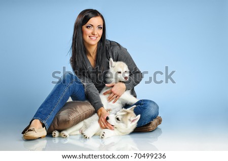 playing woman with puppies of siberian haski on blue background