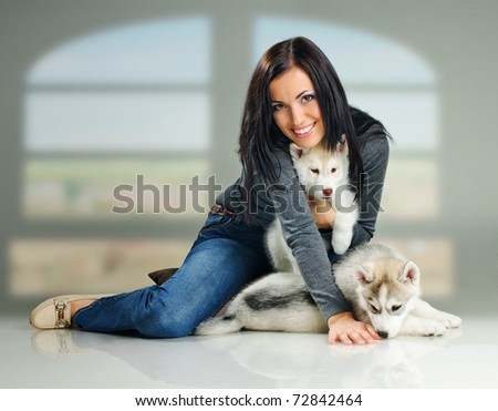 playing woman with puppies of siberian haski on gray background with window effect