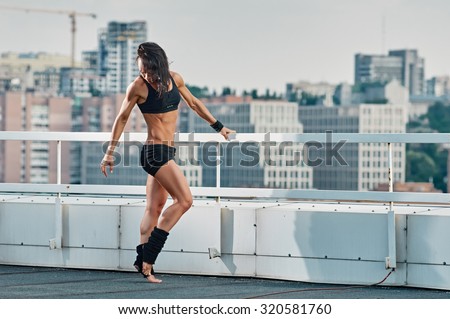 sport, fitness, exercise and lifestyle concept - woman doing sports outdoors on house-top in the city
