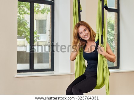 Young woman posing in anti-gravity aerial yoga green hammock. indoor fitness club