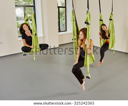 Young women posing in anti-gravity aerial yoga green hammock. indoor fitness club. break relax. shot from above