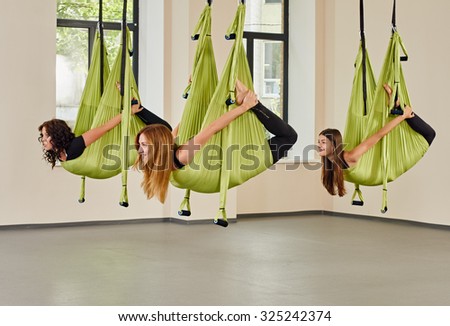 Young group women making antigravity yoga exercises. green hammocks.