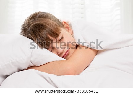 Little girl portrait on pillow in bed. sleeping, with light window background