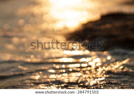 Abstract blurred colorful booked clear sea water reflecting in the sun over sunset background
