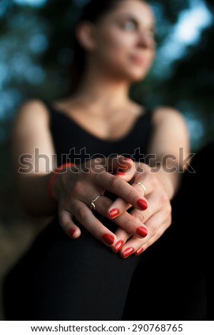 Pretty sportswoman portrait sitting on a large stone. Evening. Hands in focus.