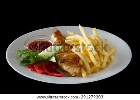 Serving dishes. French fries with barbecue and vegetables on a white plate on a black background