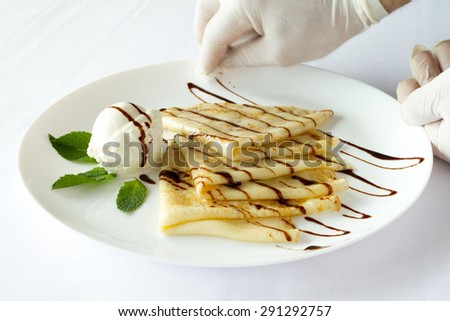 Serving dishes. Cook dish gloves cleans. Ice cream with pancakes on a white plate on a white background
