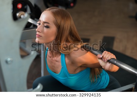 Athletic strong woman squat with bar in gym