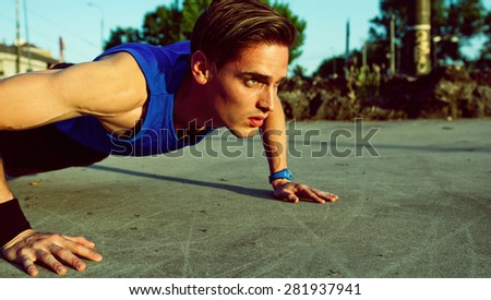 Young handsome athlete doing push ups on a beautiful sunny day