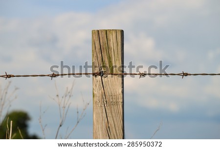 Fence post and wire in field