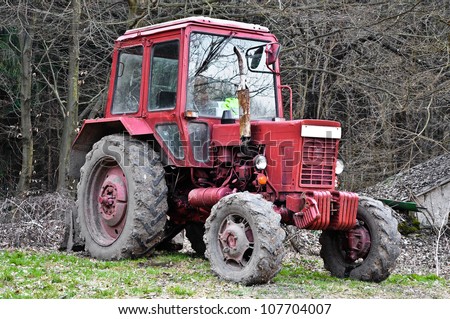 Dirty red tractor in the woods