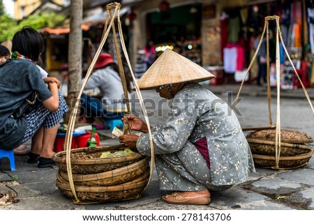 Old woman counts the money on the street. Vietnam.