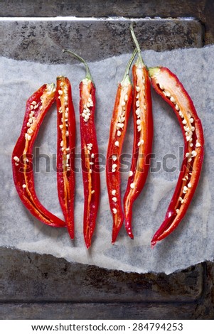 Sliced red chillies on a baking sheet with greaseproof paper