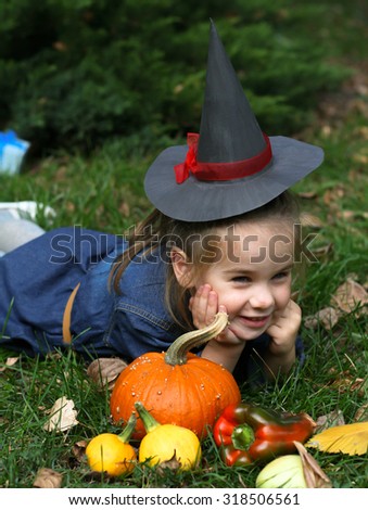 Girl with witch hat and pumpkin lying on the glass