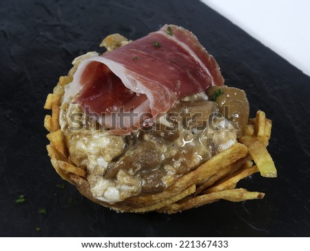 Basket of mushrooms scrambled with ham and chips on slate plate