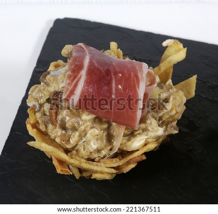 Basket of mushrooms scrambled with ham and chips on slate plate