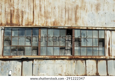 Rusted metal building or warehouse with broken window panes