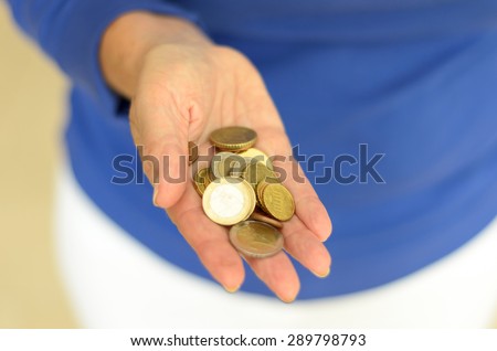 Woman holding loose change in her hand with an assortment of Euro coins as she prepares to make a money payment