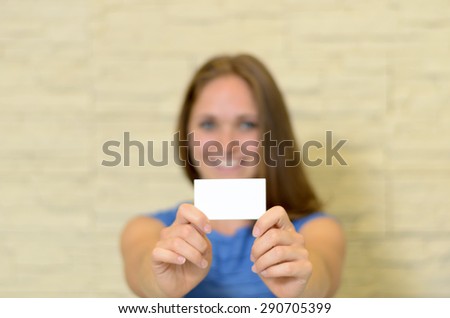 Young woman holding out a blank white business card in her extended hands with copyspace for your contact details, branding and qualifications, with focus to the card