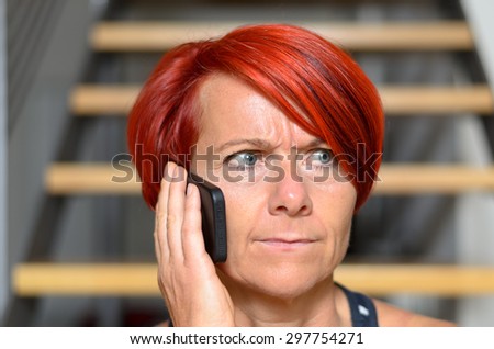 Close up Serious Redhead Adult Woman Calling Someone on her Mobile Phone While looking Into the Distance.