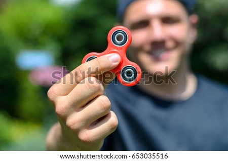 young man playing with a fidget spinner, focus on spinner