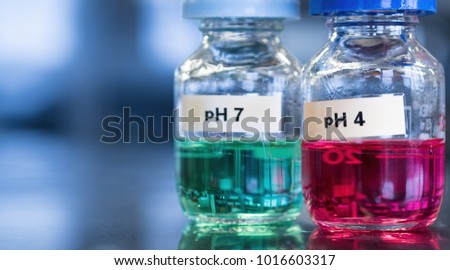 pH 7 (green) and 4 buffer (red) solutions in glass bottles. These calibration solutions are commonly found in science laboratories where meters are used to measure sample acidity or alkalinity.