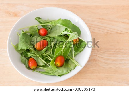 Rocket salad in white bowl on wooden background