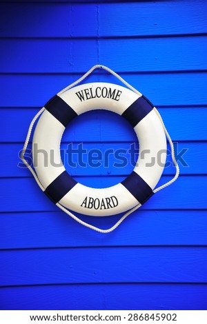 Welcome on Board - Lifebuoy with text on blue wooden background