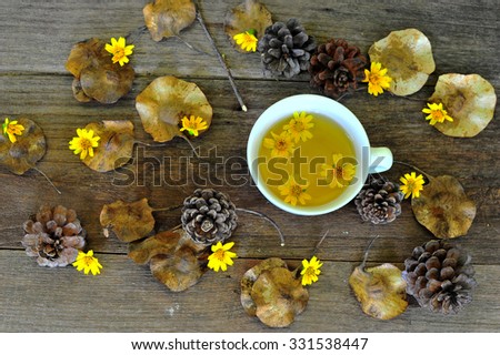 Herbal tea and yellow flowers  on old wooden table.