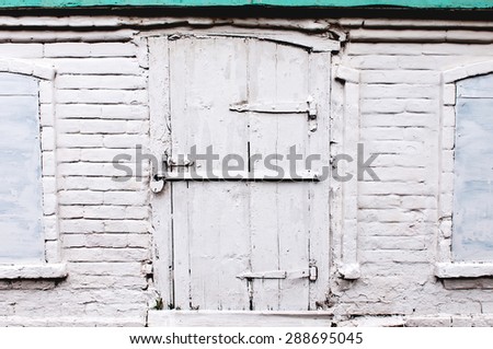 Part of brick wall with old locked door and windows