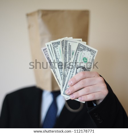 Businessman with paper bag on a head and with dollars in hand