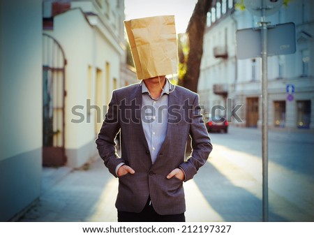 Businessman with paper bag on the head in the street