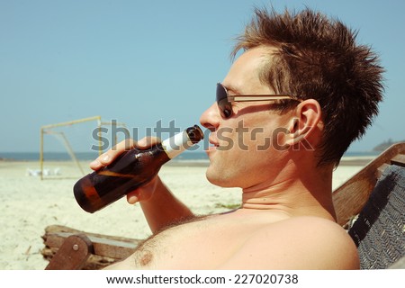 Young man drinking beer on the beach