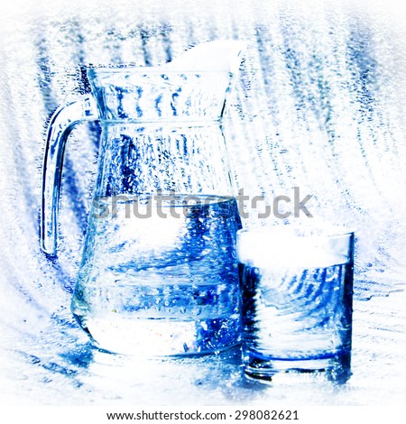 The carafe and the glass of clear water splashes and water drops