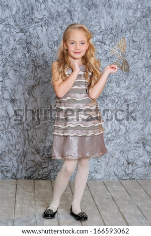 Beautiful little blonde girl posing in fashion silver dress and with carnival mask