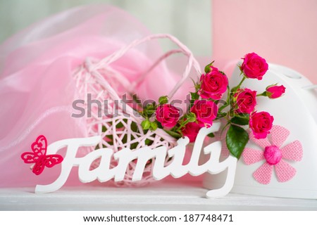 Still life with wooden family sign and delicate roses in pink colors