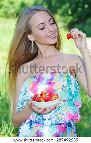 Summer happiness concept with beautiful smiling woman holding strawberry full bowl
