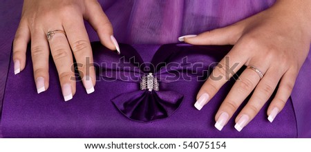 Beautiful hands with french manicure holding purple purse