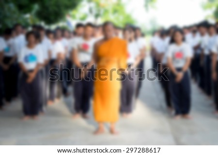 Student group meditation by walk with monk in temple defocused background.