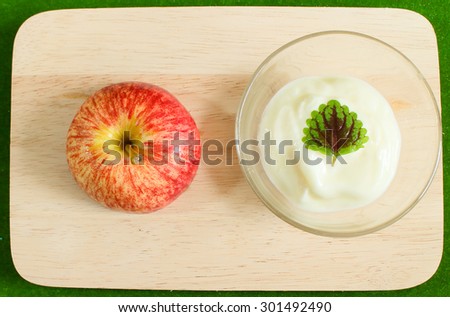 Natural low-fat yogurt with apple  in the glass cup on wood plate