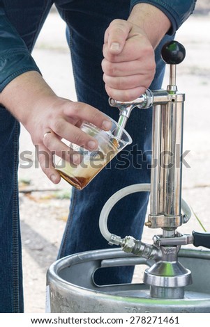 Filling plastic glass with beer from metal beer keg